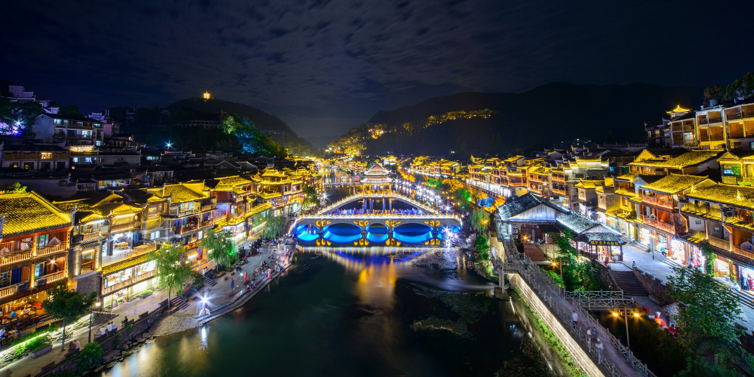 Fenghuang iluminada à noite às margens do rio